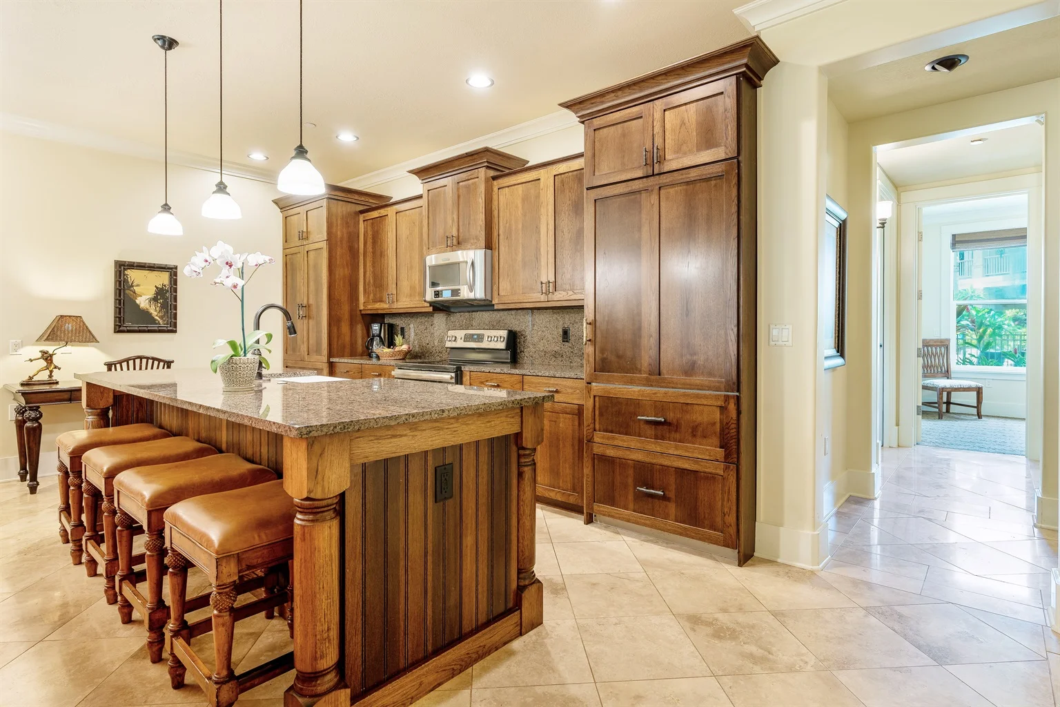 Kitchen with wooden cabinets, granite countertop, and leather bar stools, showcasing a stylish dining area in a luxury vacation rental in Kauai.