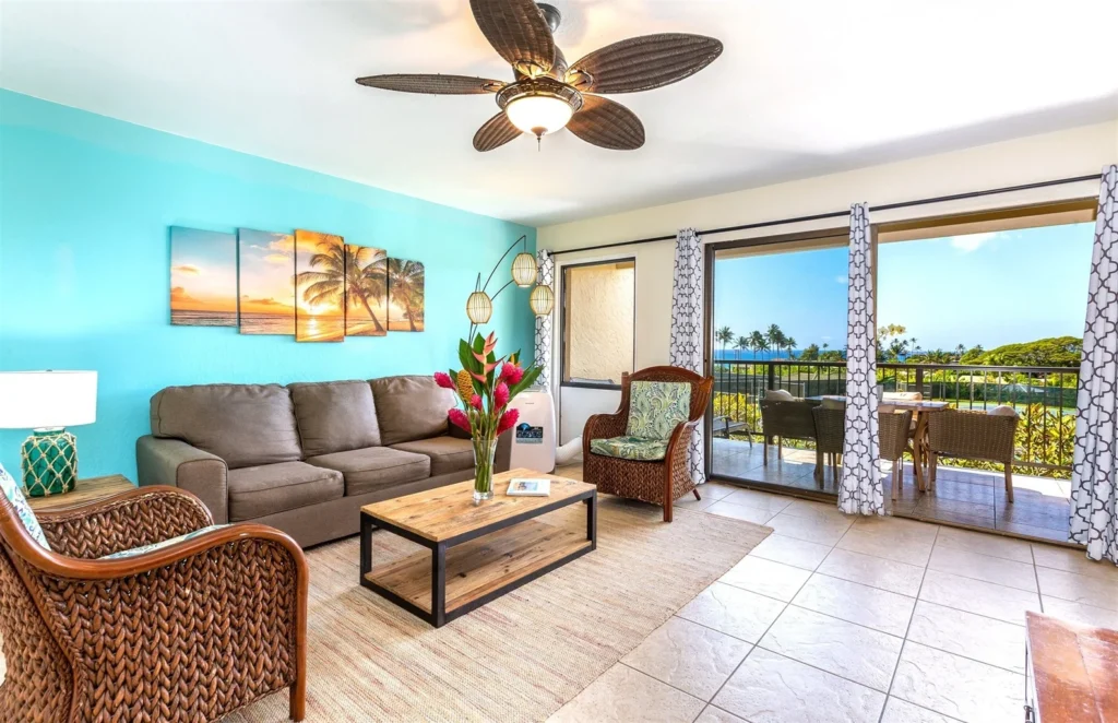 Spacious ocean-view living area in a luxurious 1-bedroom, 1-bathroom suite, featuring a brown sofa, tropical decor, and a welcoming ambiance ideal for families or couples.
