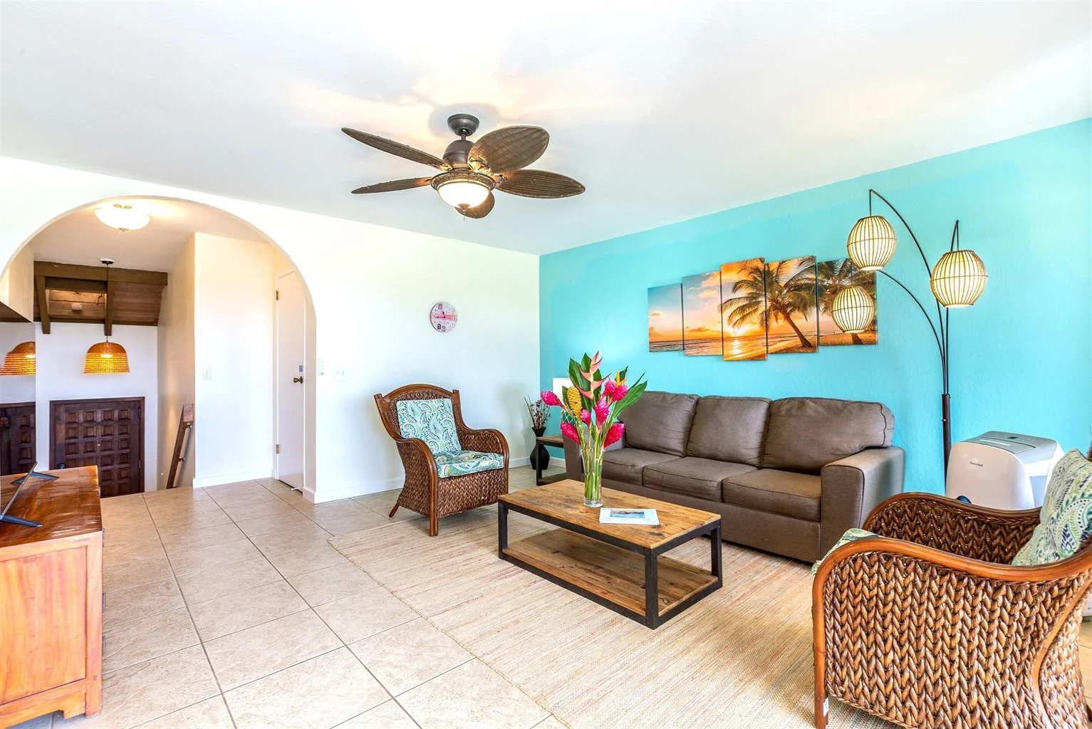 Spacious ocean-view living area in a luxurious 1-bedroom, 1-bathroom suite, featuring a brown sofa, tropical decor, and a welcoming ambiance ideal for families or couples.
