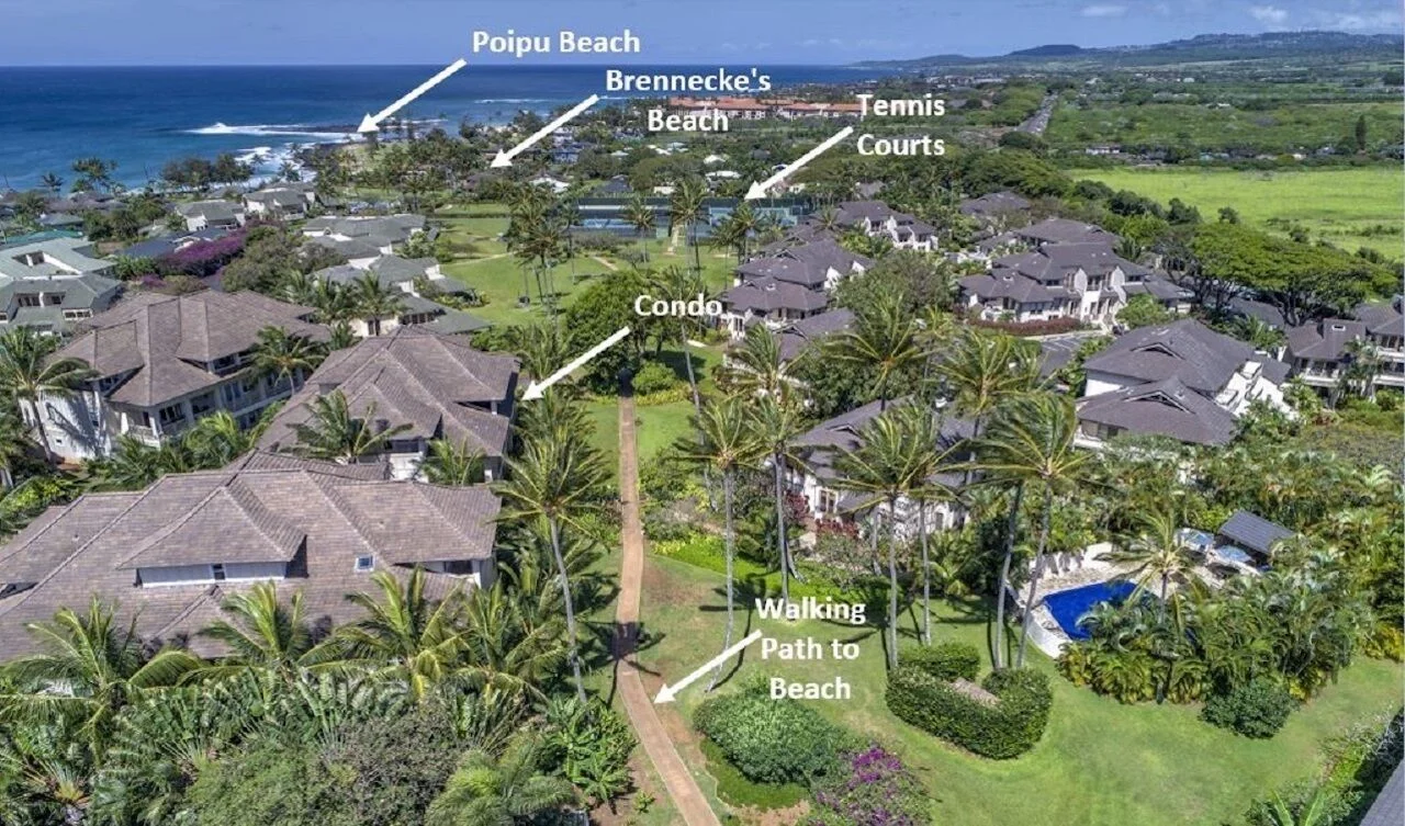 Aerial view of a luxury resort in Kauai, featuring a walking path to the beach, surrounding palm trees, and nearby amenities like tennis courts and condos, emphasizing the island