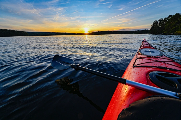 Kayak on tranquil water at sunset, showcasing adventure opportunities in Kauai's stunning natural landscape.