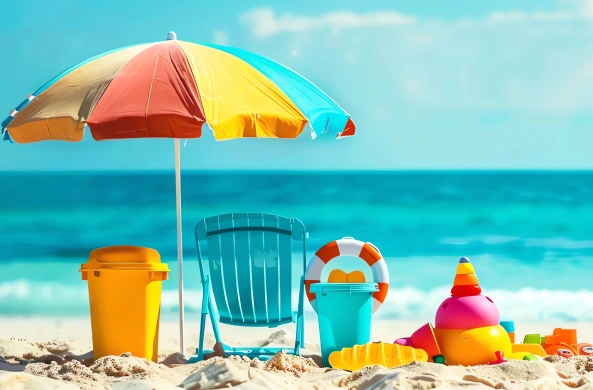 Colorful beach umbrella, turquoise chair, and children's beach toys on sandy shore, evoking family-friendly vacation vibes in Kauai.